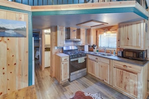 A compact kitchen with wooden cabinets, a stainless steel stove, and a microwave. - Peaceful Lake Almanor Hideaway, Fish, Hunt + Hike! (Westwood)