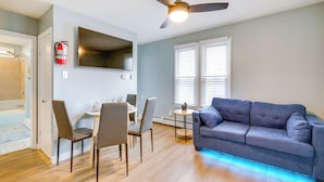 A modern living room with a grey sofa, dining table, chairs, and a ceiling fan. - Centrally Located Ocean City Apt < 1 Mi to Beaches (Ocean City)
