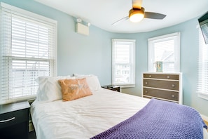 Une chambre à coucher avec un lit, une commode et un ventilateur de plafond.