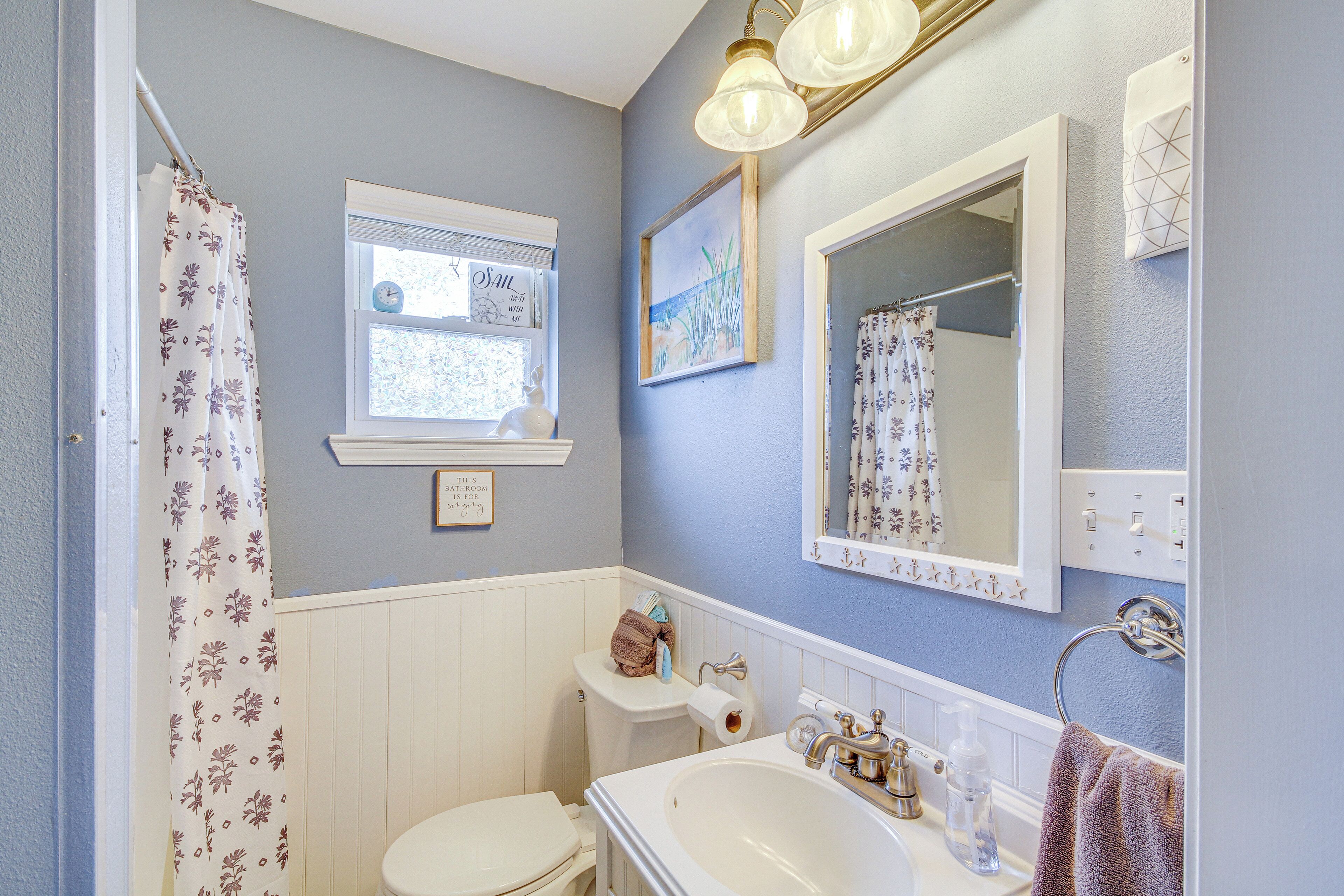 Een badkamer met toilet, wastafel en douchegordijn.