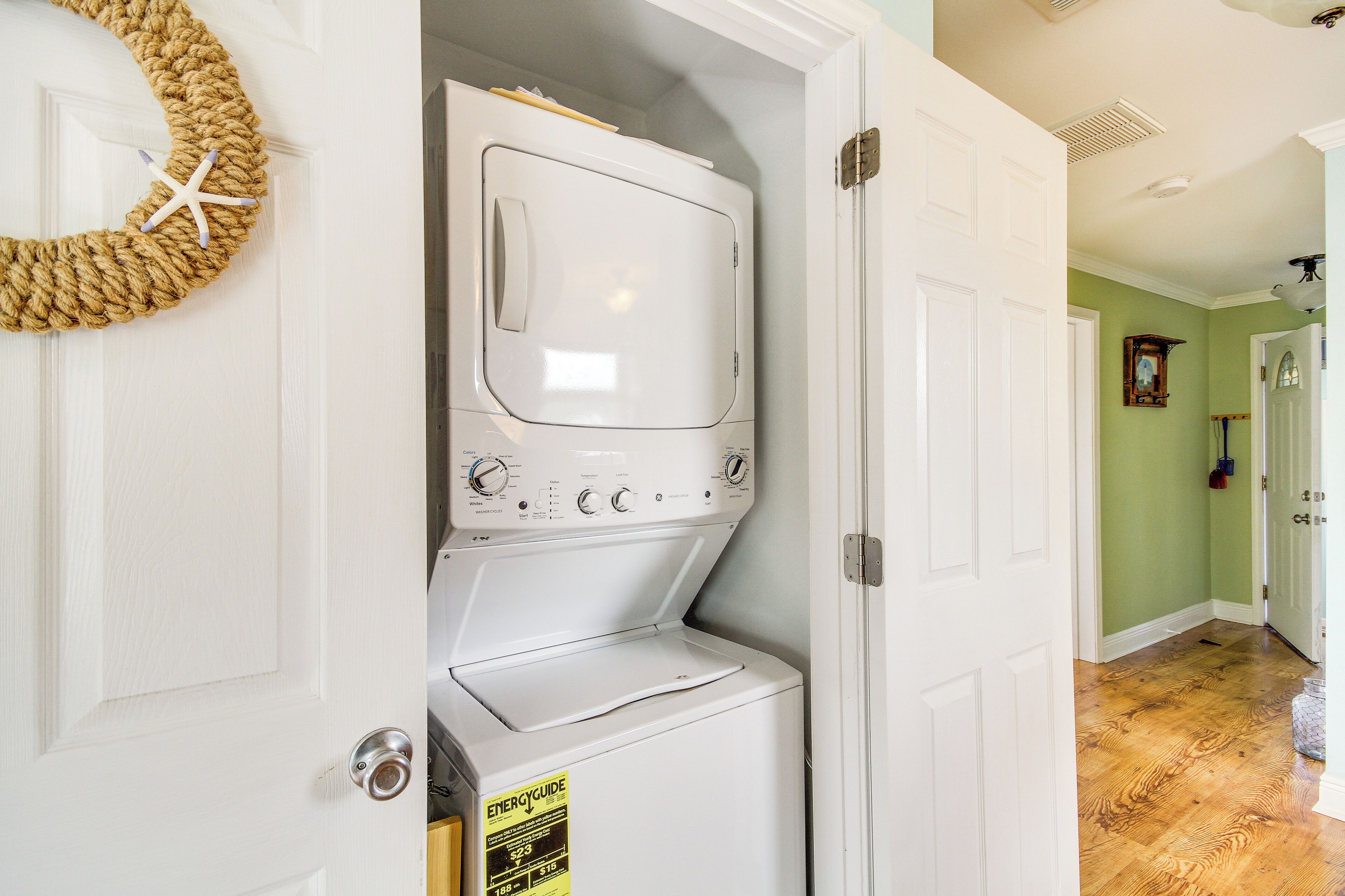 A laundry room with a front-loading washer and dryer, a starfish decoration, and a door with a white frame.