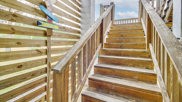 A wooden staircase with a handrail and a wooden fence with directional signs. - Waterfront Bay St Louis Home w/ Private Dock! (Bay St Louis)
