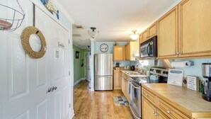 A kitchen with wooden cabinets, stainless steel appliances, and a hanging light fixture. - Waterfront Bay St Louis Home w/ Private Dock! (Bay St Louis)