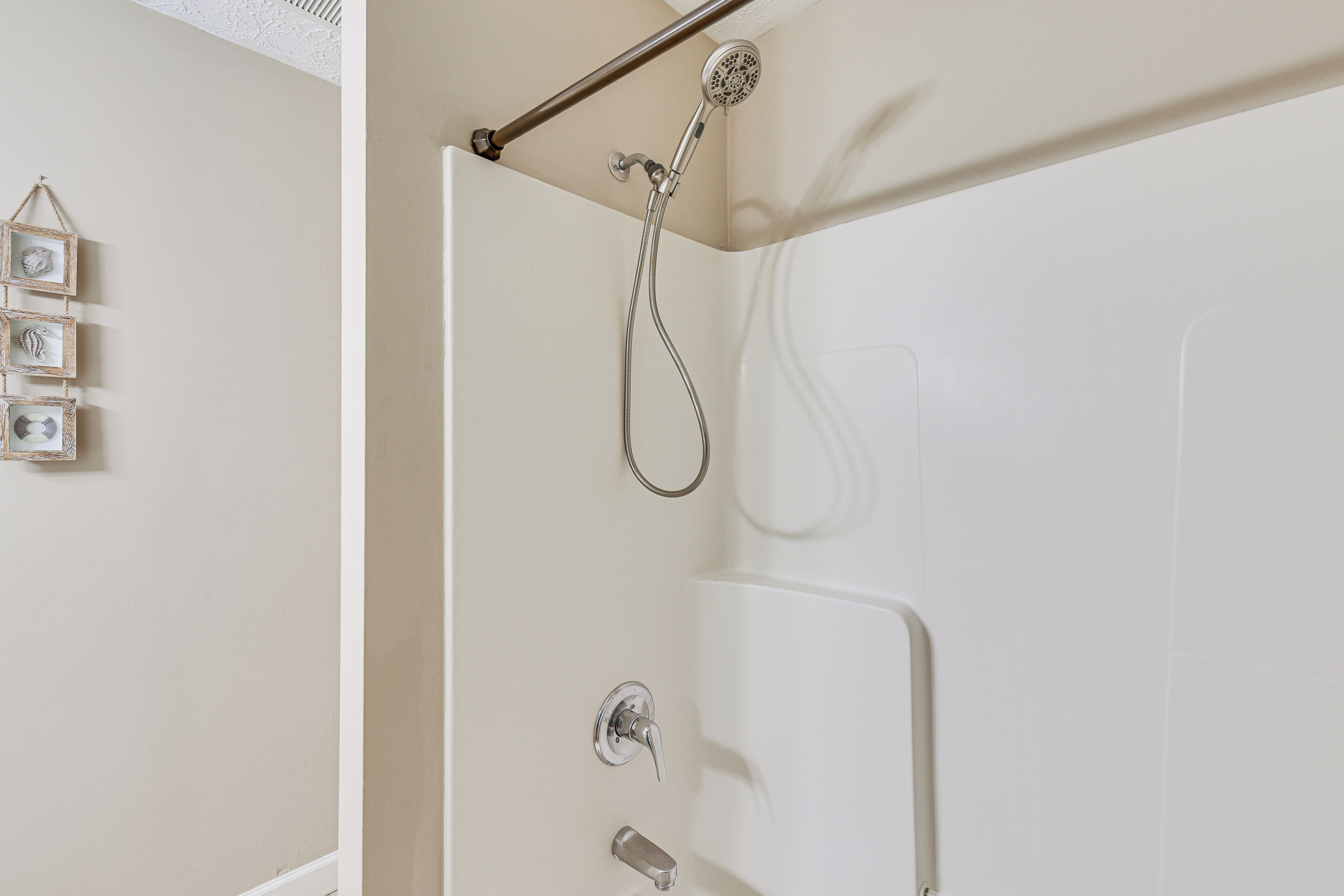 A shower with a handheld showerhead and a wall-mounted faucet.