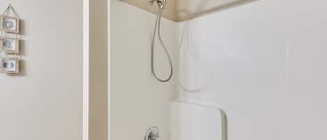 A shower with a handheld showerhead and a wall-mounted faucet.