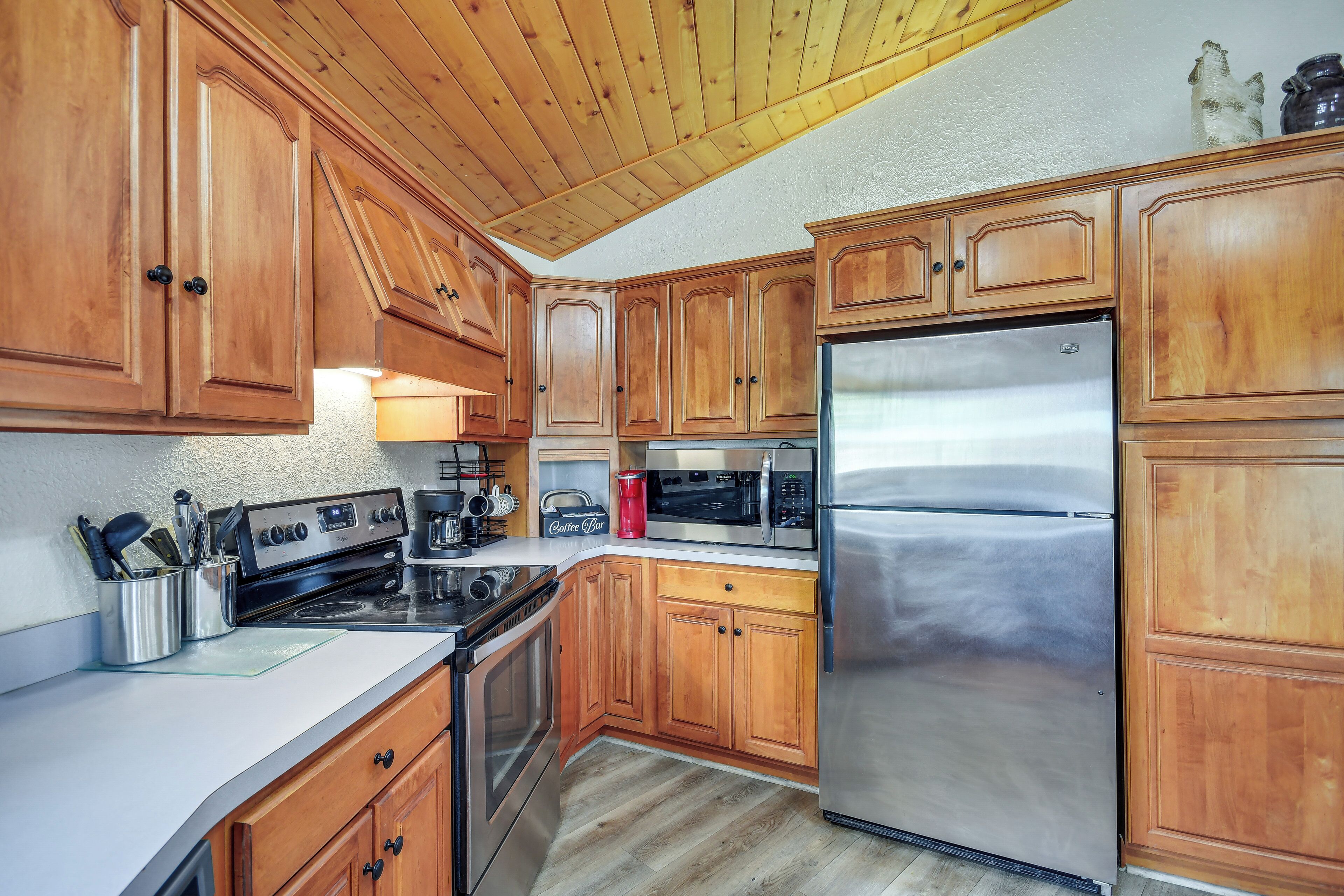 A kitchen with wooden cabinets, stainless steel appliances, and a wooden ceiling.