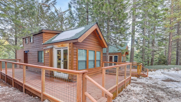 Una cabaña de madera con terraza, rodeada de árboles.