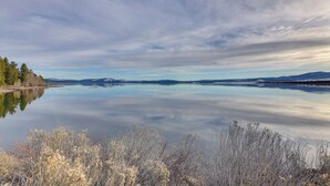 Un lago tranquilo con montañas al fondo y un cielo despejado.