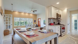 Una cocina moderna con armarios blancos, un microondas y un horno. Hay una mesa de comedor con platos y tazas.