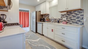 Una cocina moderna con armarios blancos, estufa integrada y salpicadero de azulejos.