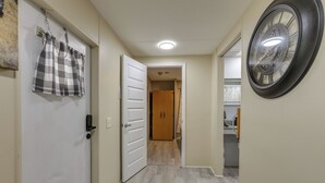 Käytävä, jossa on ruutukuviollinen verho, ovi ja seinäkello.