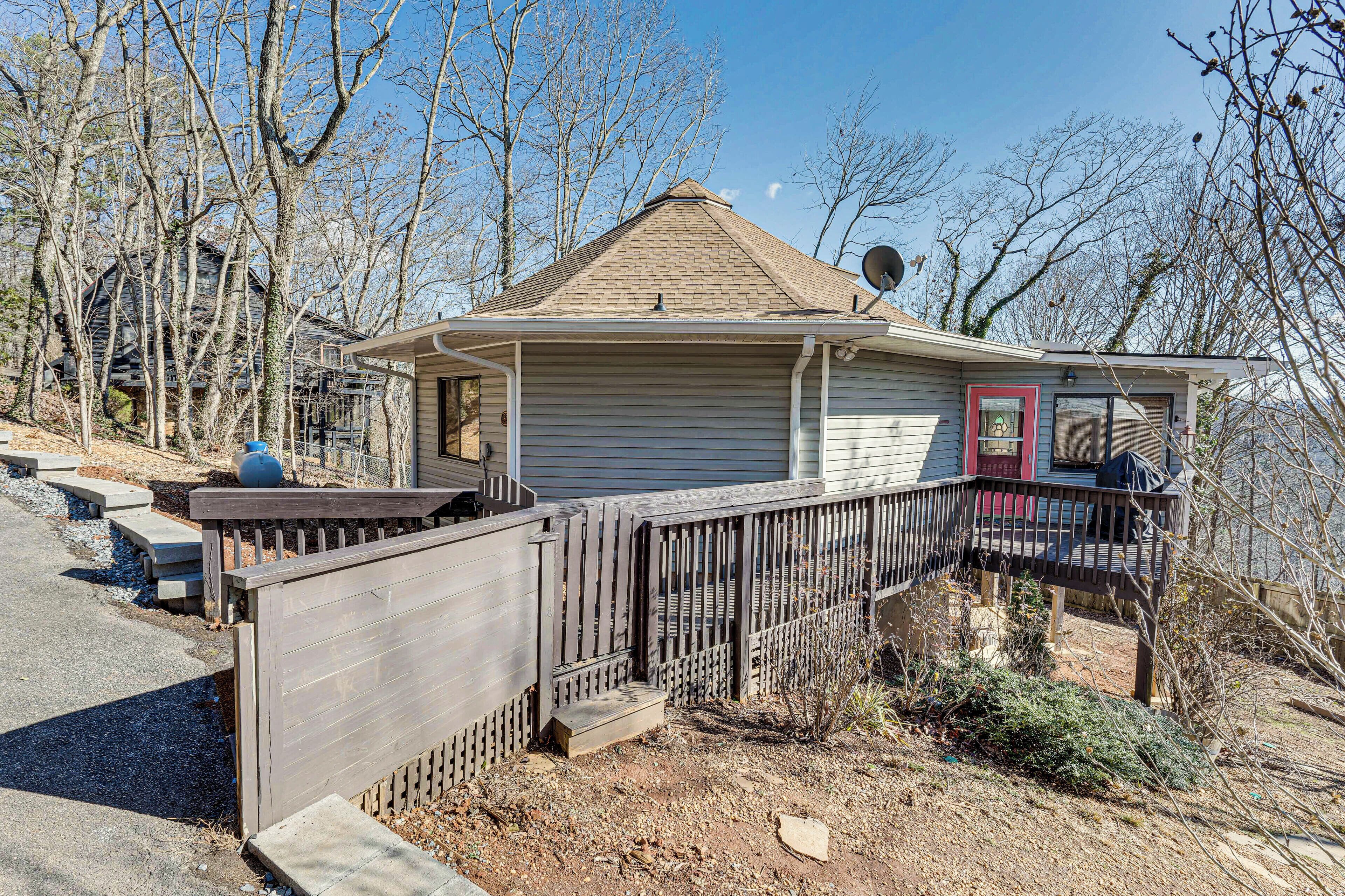 A single-story house with a fenced deck, a satellite dish, and a small porch.