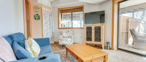 Un soggiorno accogliente con un divano blu, un tavolino in legno, un tappeto decorato, un televisore e una poltrona in vimini.