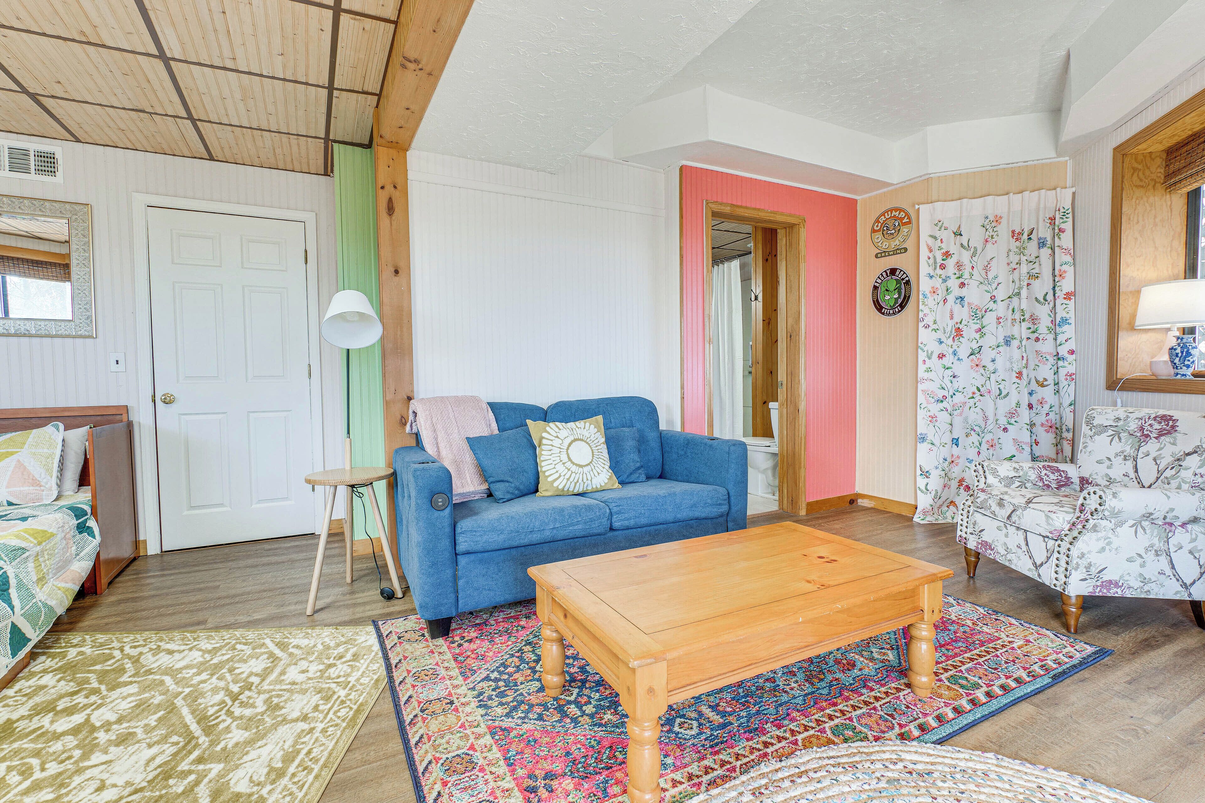 A cozy living room with a blue sofa, a wooden coffee table, and a patterned rug.