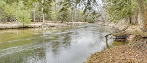 A river flowing through a forested area with trees and a grassy bank.