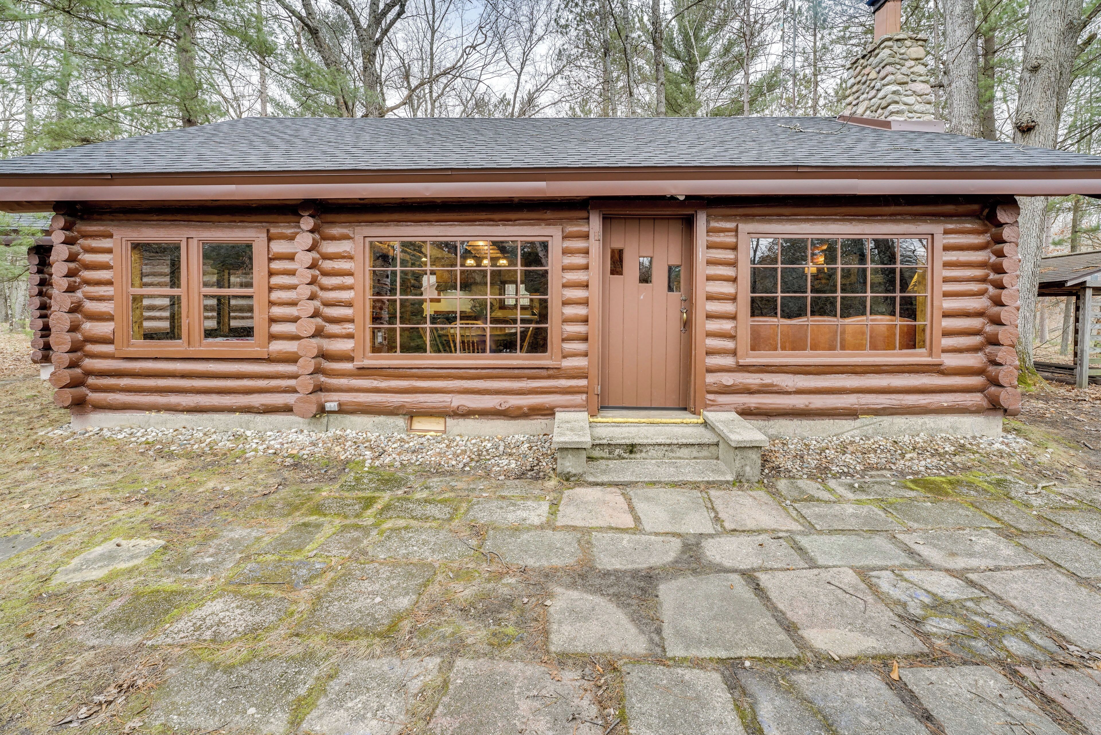 A log cabin with a stone foundation, wooden windows, and a door.