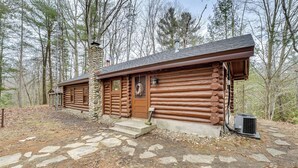A log cabin with a stone pathway leading to the entrance, surrounded by trees.