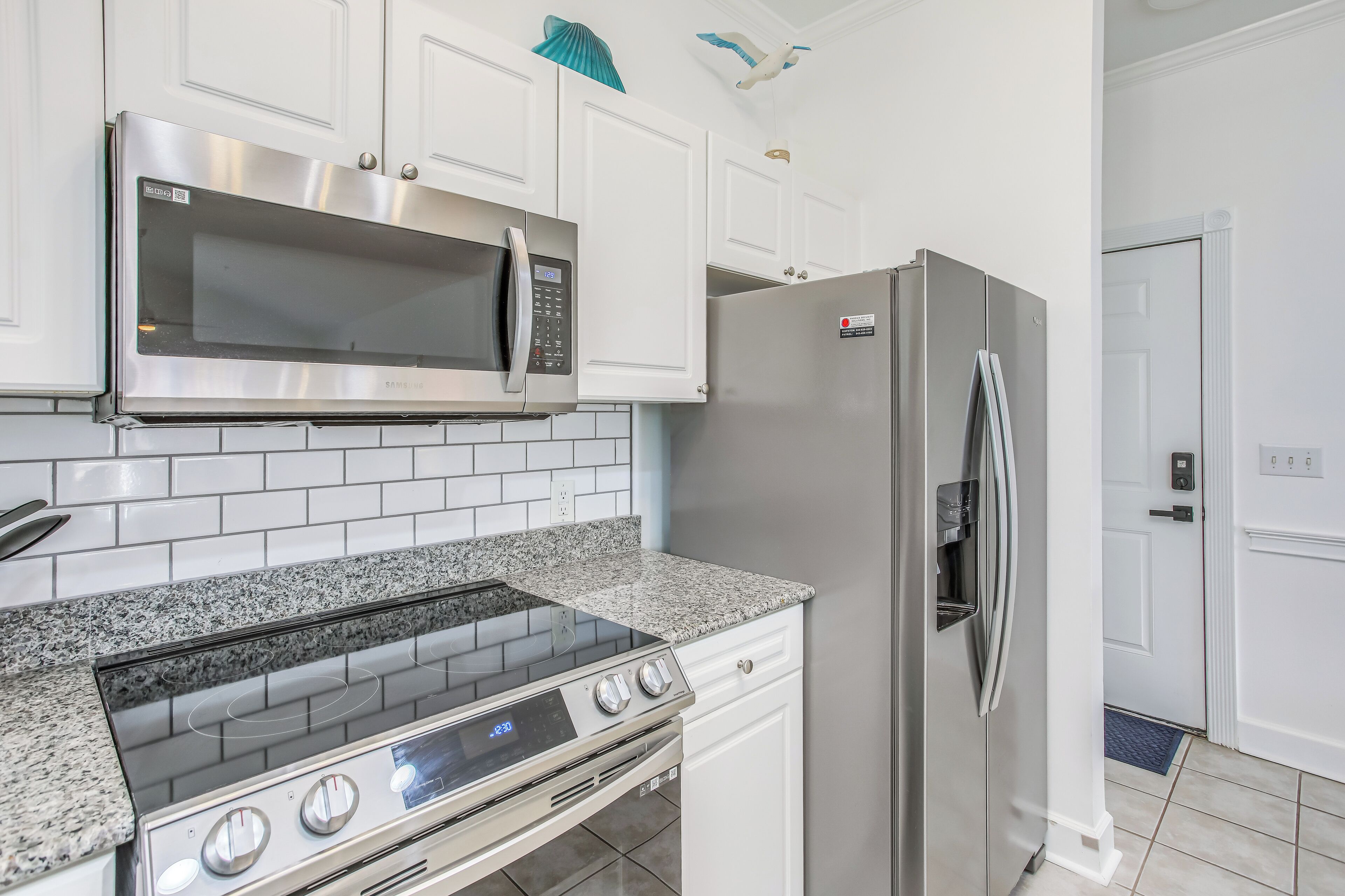 A kitchen with white cabinets, a stainless steel microwave, a built-in oven, and a refrigerator.