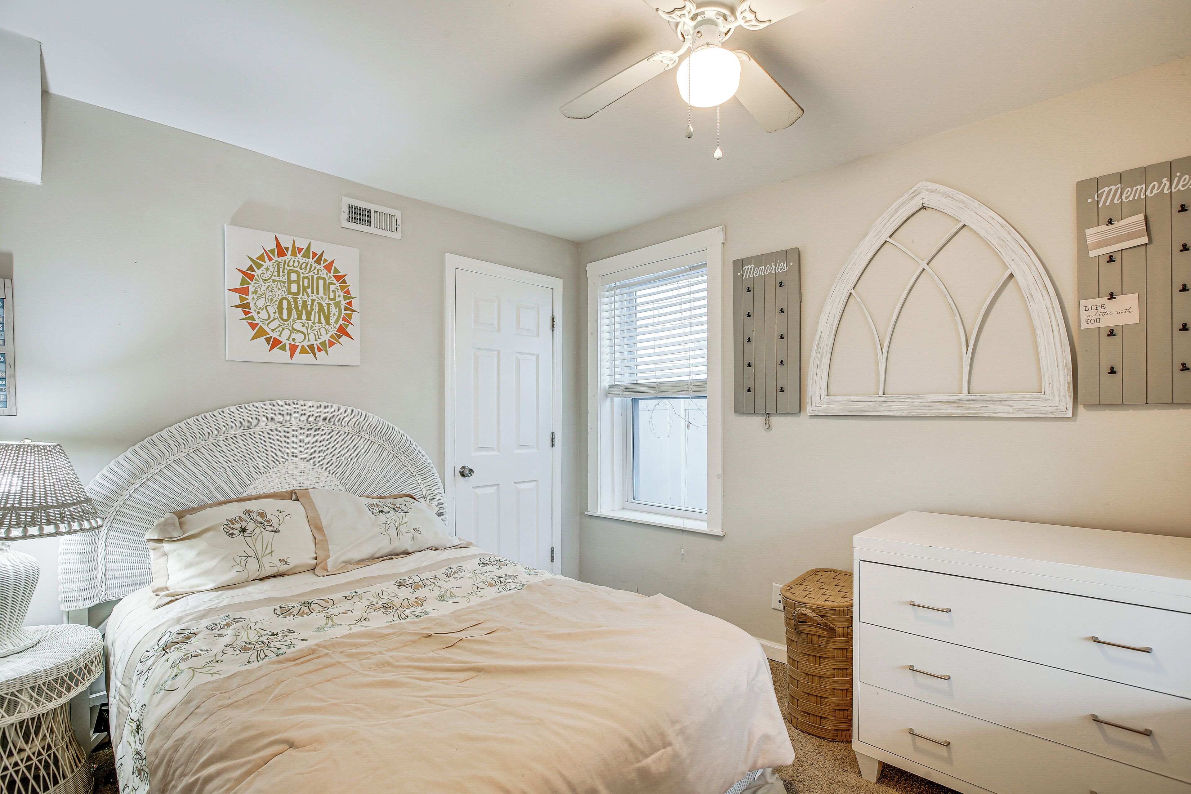A bedroom with a bed, a dresser, a window, and wall decorations.