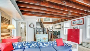 A room with a blue and white patterned sofa, red pillows, a red cabinet, and a staircase leading to another level. - Wildwood Retreat w/ 2 Balconies: 5 Blocks to Beach (Wildwood)