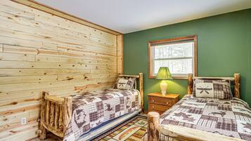 Una habitación con dos camas de madera, una pared verde y una ventana.