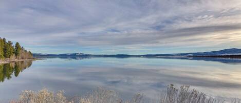 Un lago tranquilo con montañas al fondo y un cielo despejado.