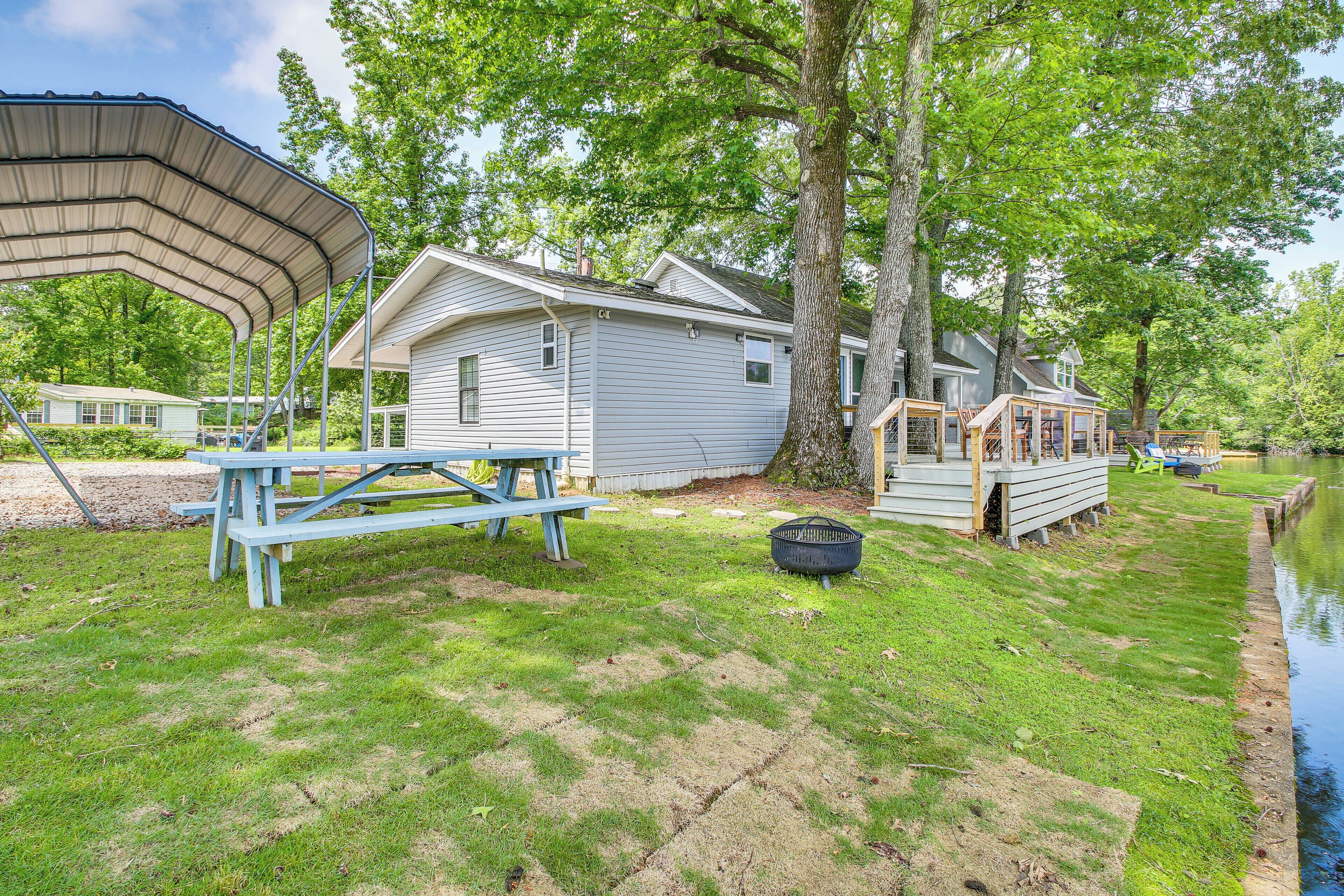 A lakeside cabin with a covered picnic table, a deck, and a small boat dock.