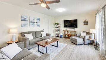 A living room with a sofa set, a coffee table, a TV, and a ceiling fan.