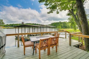 A wooden deck with a table and chairs overlooking a lake, a covered pavilion, and a tree. - Waterfront Home on Lake Hamilton w/ Dock & 2 Decks (Royal)