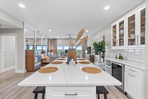 A modern kitchen with a large island, white cabinetry, and a view to the outside. - Shell Seeker - Gulf-View Condo at Tops'l Resort | Pool, Beach Access, Hot Tub, & More! BM 702 (Miramar Beach)