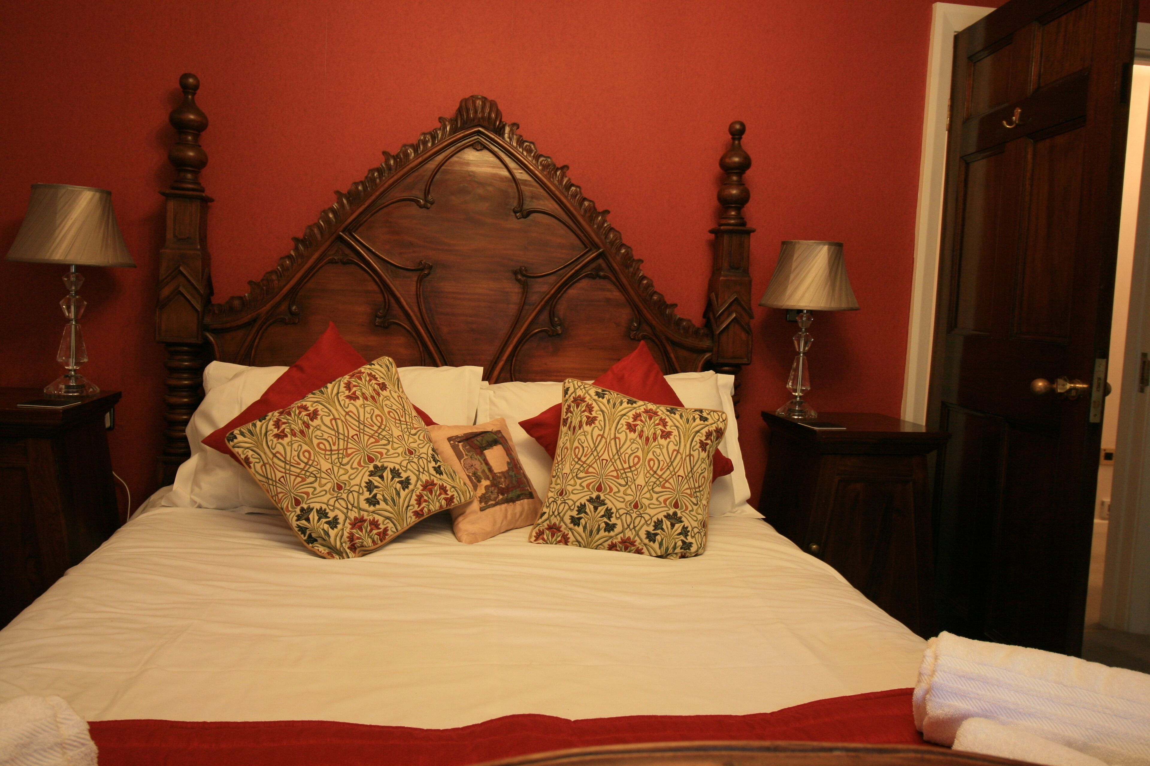 A bed with a wooden headboard, two bedside lamps, and patterned pillows.
