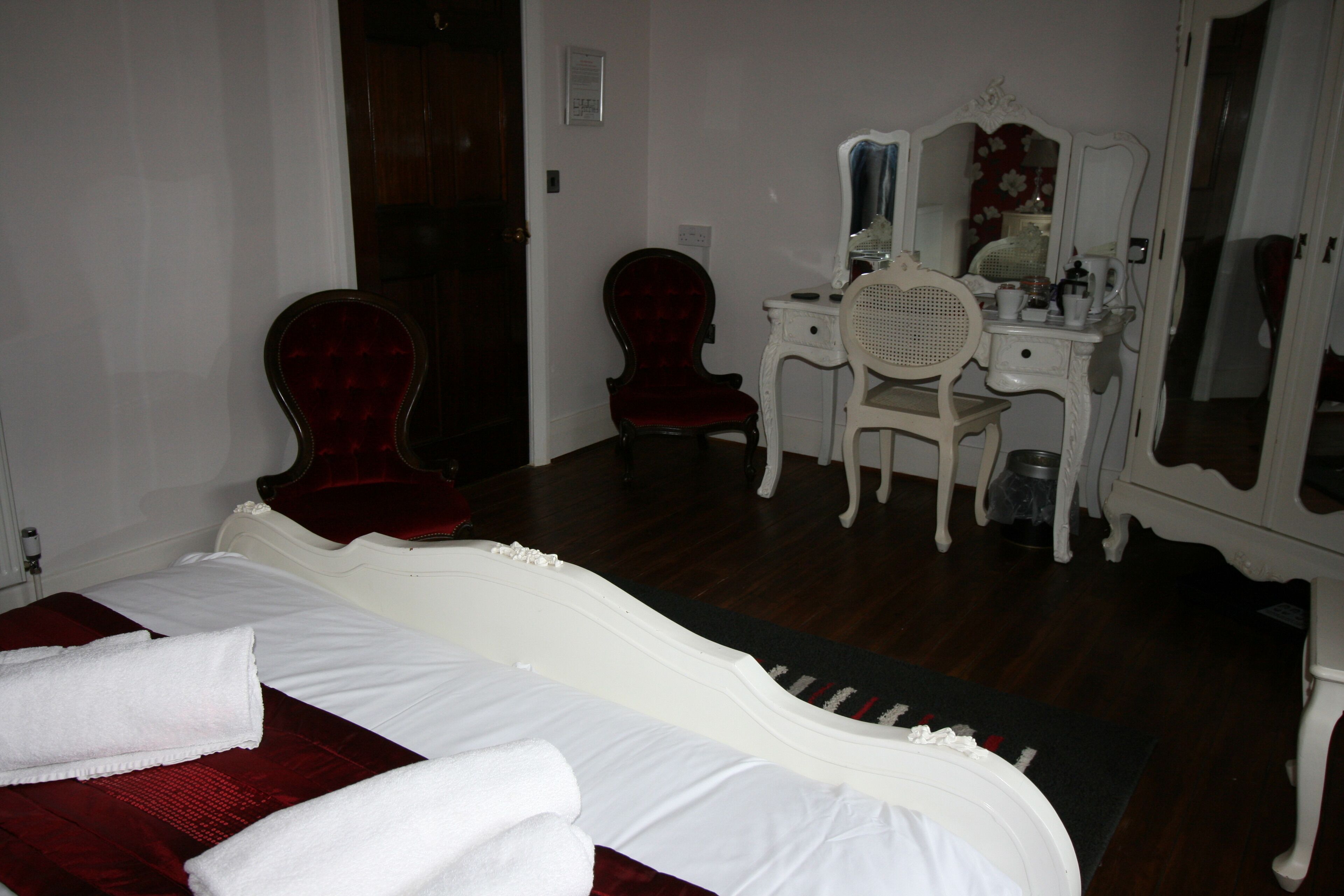 Une chambre à coucher avec un lit, une coiffeuse avec un miroir et une chaise.