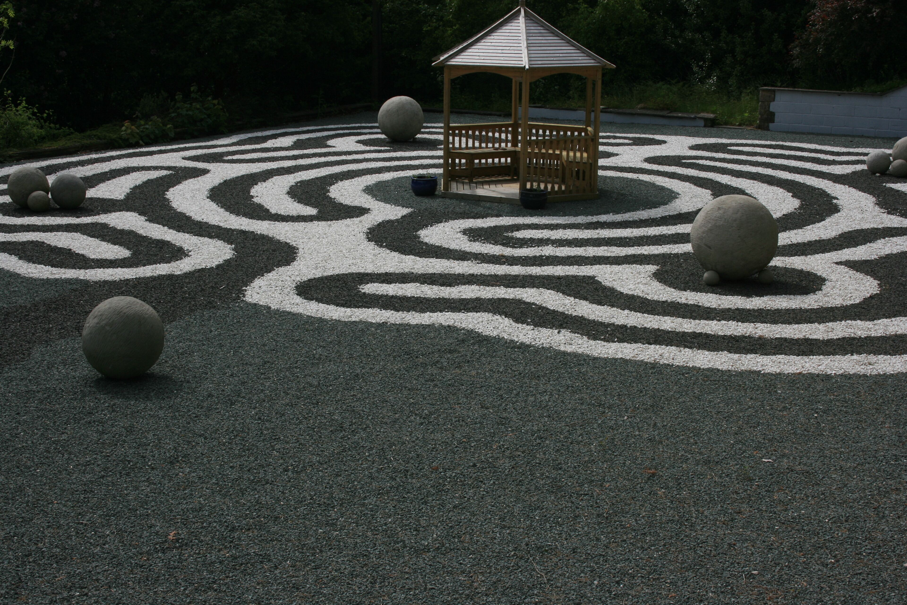 A gazebo surrounded by a circular gravel pattern with evenly spaced stones.