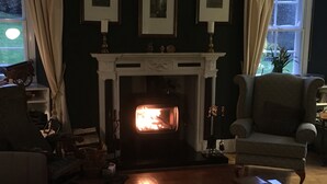 A cozy living room with a fireplace, a comfortable armchair, and a coffee table. - High Dalby House (Pickering)