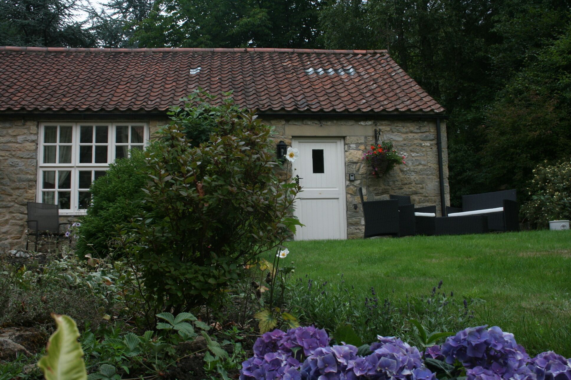 A stone cottage with a tiled roof, a white door, and a window.