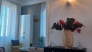 Una sala de estar con un sofá, una mesa de centro, una consola negra con un florero, una lámpara y un armario.