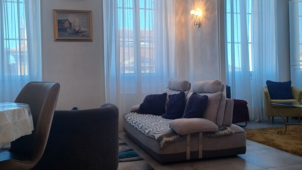 Una sala de estar con un sofá, sillones, una mesa y un cuadro en la pared.
