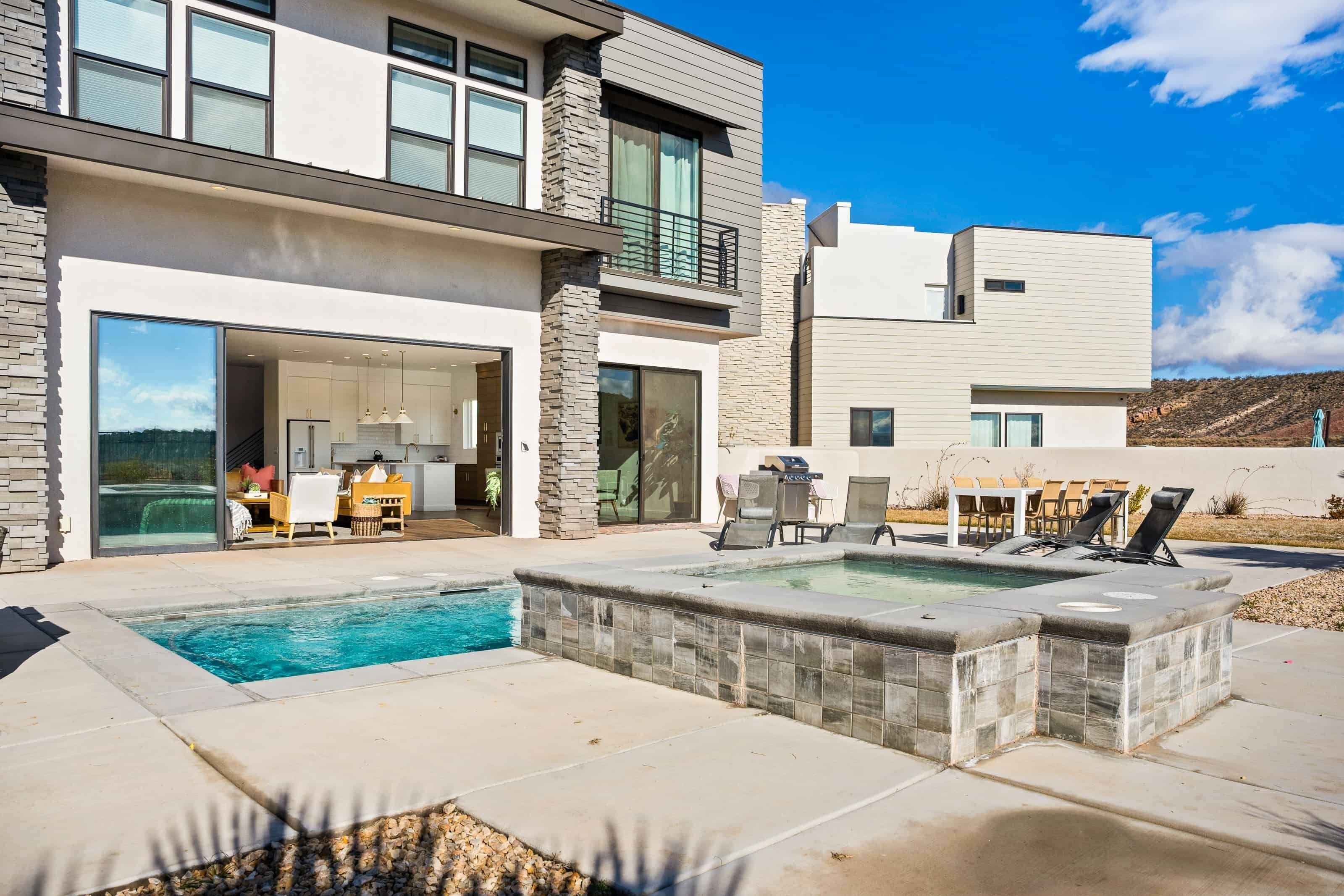 A modern two-story house with a swimming pool, outdoor seating, and a patio area.