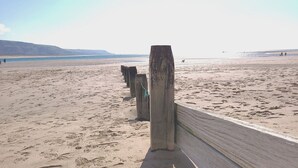A sandy beach with wooden posts and a wooden walkway. - Tawelfan (Llwyngwril)