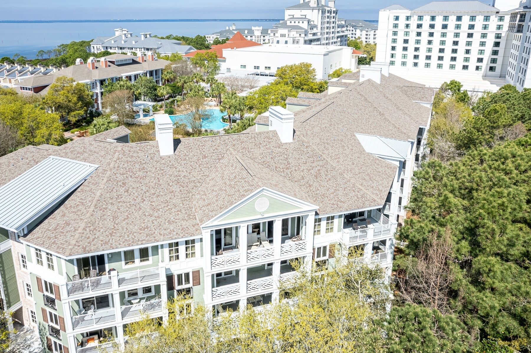 A multi-story building with a rooftop pool, surrounded by trees and other buildings.