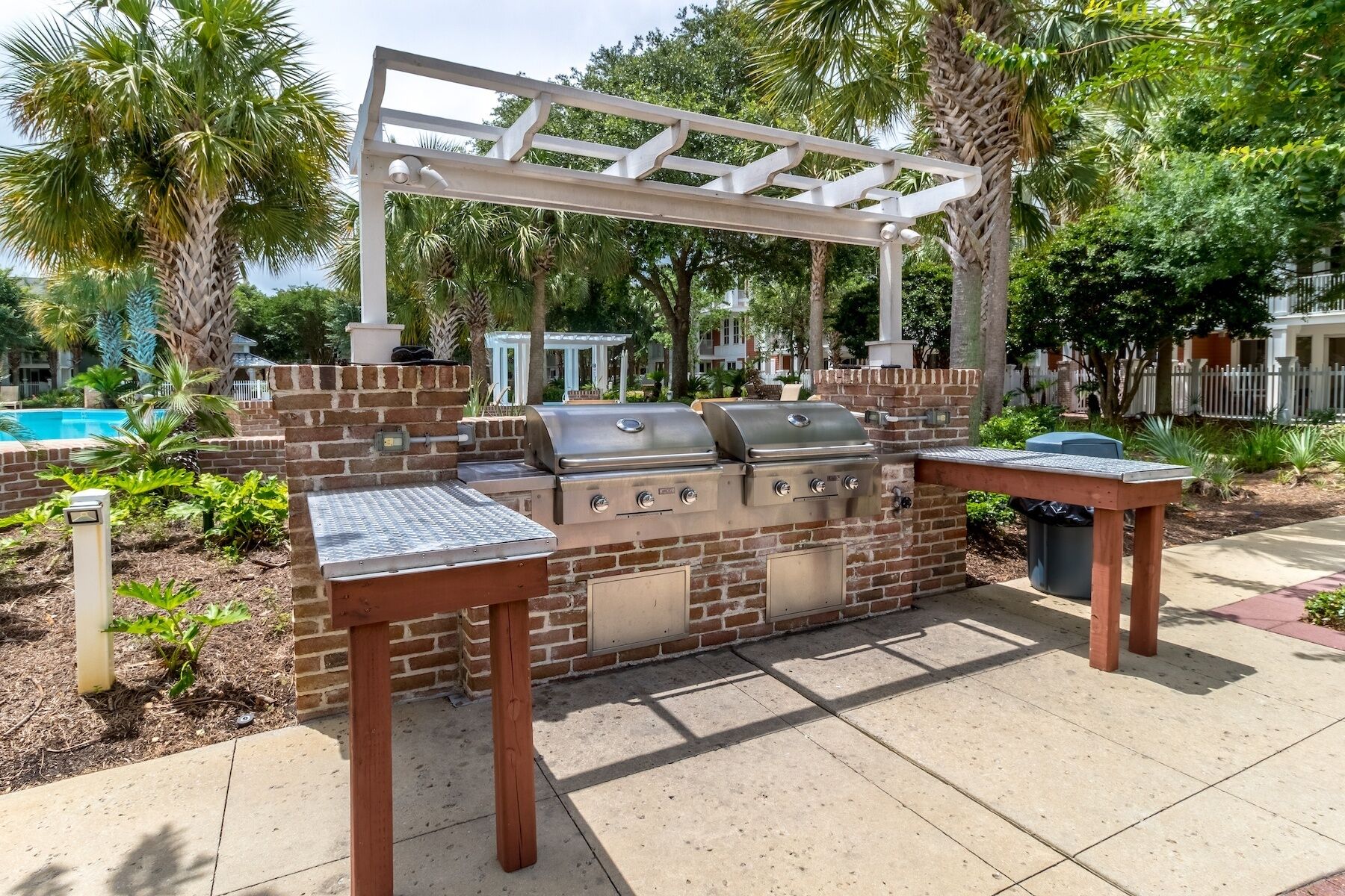 Un espace barbecue extérieur avec un mur en briques, deux barbecues à gaz et une pergola.