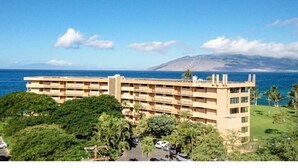 Ein mehrstöckiges Hotel mit Blick auf das Meer und einem Berg im Hintergrund.