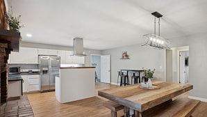A spacious kitchen with white cabinets, a large island, and a built-in brick oven.