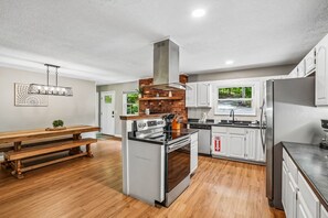 Een moderne keuken met een centraal eiland, roestvrijstalen apparatuur en houten vloeren.