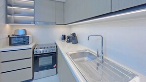 Una cocina moderna con horno empotrado, microondas y pileta de acero inoxidable.