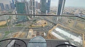Un edificio de gran altura con vistas a un paisaje urbano, que incluye varios rascacielos y una autopista.