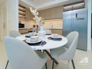 A modern kitchen with a built-in refrigerator, a dining table set with white plates and bowls, and a vase with white flowers. - Burj Crown Luxury 2bedroom Balcony (Dubai)