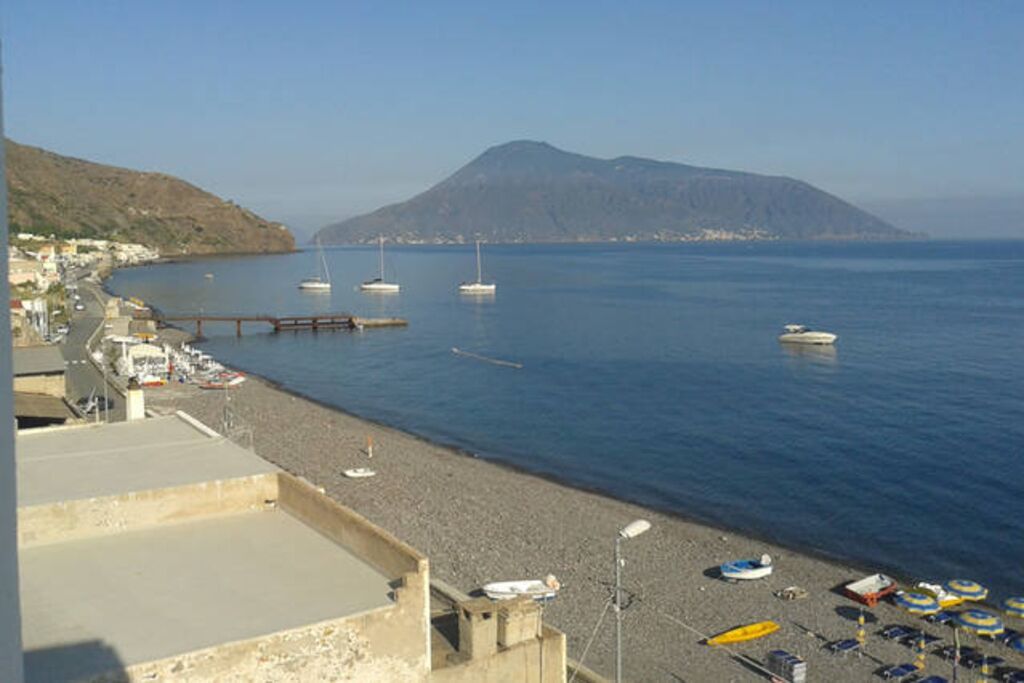 A coastal area with boats, a pier, and a mountain in the background.
