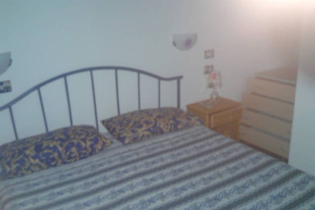 Une chambre à coucher avec un lit, une commode et une table de chevet.