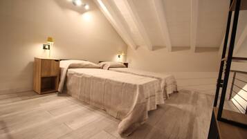 A bedroom with two beds, wooden nightstands, and wall-mounted lamps.